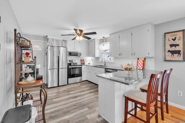 kitchen with appliances with stainless steel finishes, tasteful backsplash, sink, dark stone counters, and kitchen peninsula