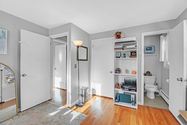 bathroom with hardwood / wood-style flooring, a baseboard radiator, and toilet