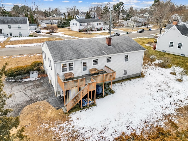 snow covered back of property with a wooden deck