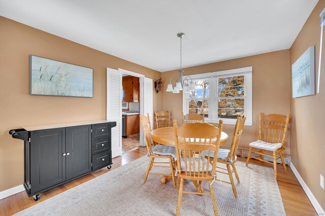 dining space featuring a baseboard radiator, a chandelier, and light wood-type flooring