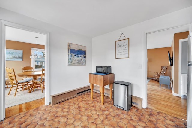 home office with hardwood / wood-style flooring, a baseboard radiator, and an inviting chandelier