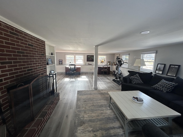 living room featuring brick wall, a wealth of natural light, a brick fireplace, and hardwood / wood-style floors