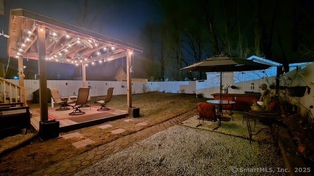 yard at night with a jacuzzi and a patio area