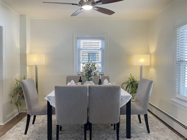 dining room with ceiling fan, a baseboard radiator, wood-type flooring, and ornamental molding