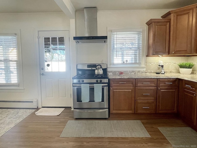 kitchen featuring a baseboard radiator, wall chimney exhaust hood, dark hardwood / wood-style floors, and stainless steel range with gas cooktop