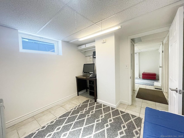 basement with a drop ceiling and light tile patterned floors