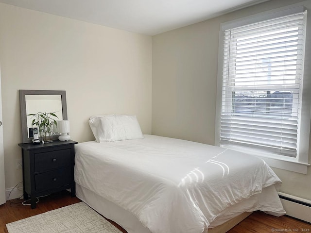 bedroom with a baseboard radiator and dark hardwood / wood-style floors