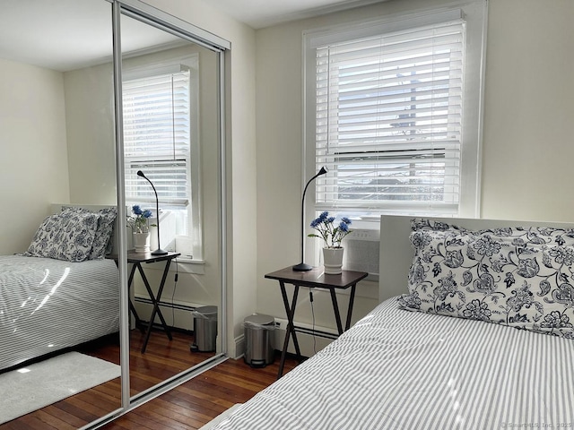 bedroom with multiple windows, dark wood-type flooring, and baseboard heating