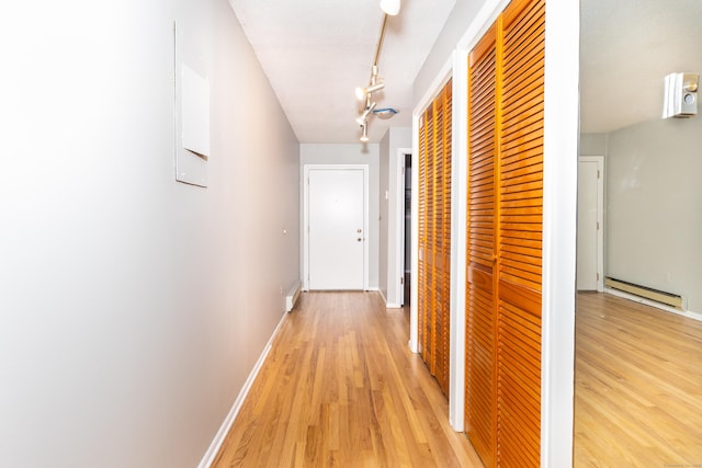 corridor featuring a baseboard radiator, light hardwood / wood-style floors, and rail lighting