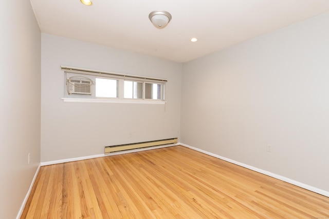 empty room featuring a baseboard heating unit, hardwood / wood-style floors, and a wall unit AC