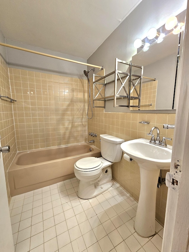 bathroom with tile walls, tiled shower / bath combo, tile patterned floors, and toilet