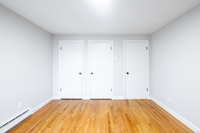 unfurnished bedroom featuring light hardwood / wood-style flooring and a baseboard heating unit