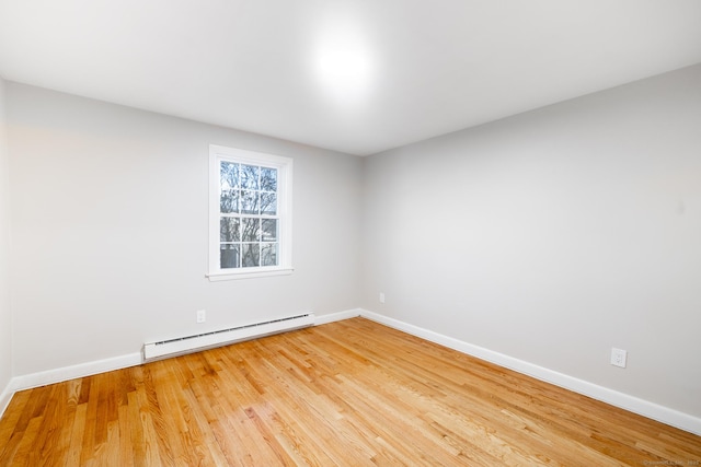 empty room with baseboard heating and light hardwood / wood-style flooring