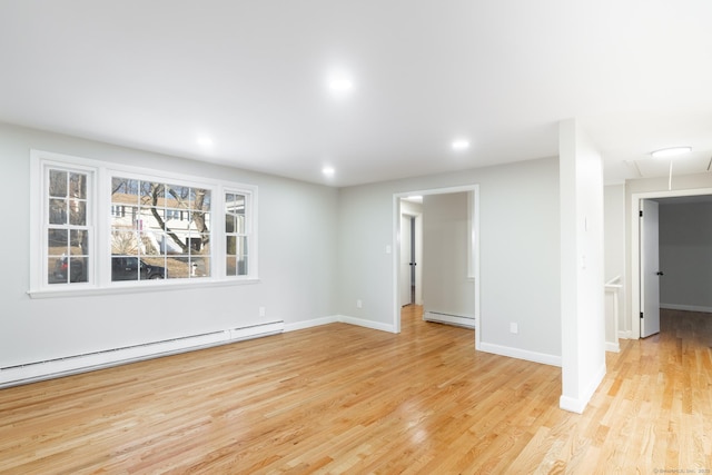 spare room with baseboard heating and light hardwood / wood-style flooring