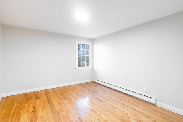 empty room featuring a baseboard radiator and light wood-type flooring