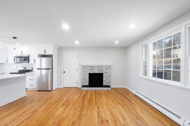 unfurnished living room featuring a fireplace, light hardwood / wood-style flooring, and baseboard heating