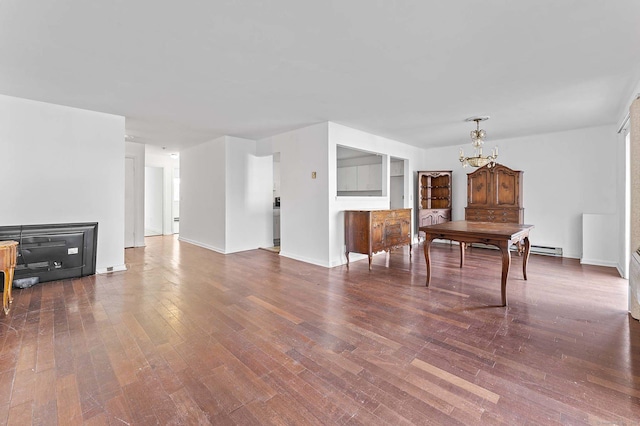 living room with an inviting chandelier, wood-type flooring, and a baseboard heating unit