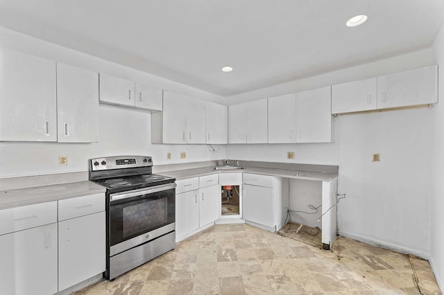 kitchen with electric stove, sink, and white cabinets