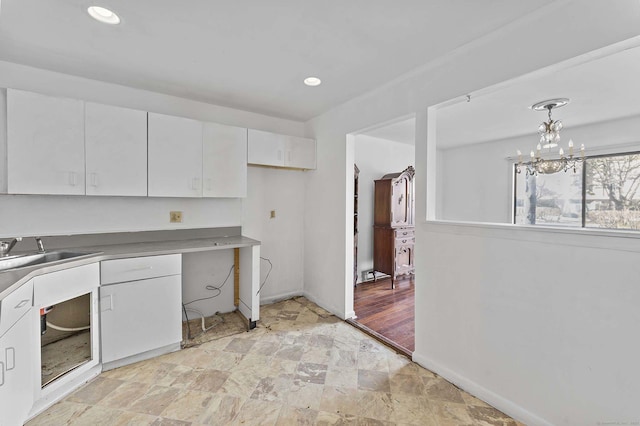 kitchen featuring pendant lighting, a notable chandelier, sink, and white cabinets