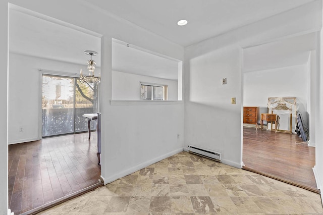 unfurnished room featuring baseboard heating, an inviting chandelier, and hardwood / wood-style floors