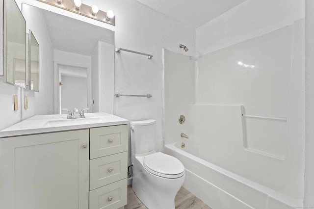 full bathroom featuring hardwood / wood-style flooring, vanity, tub / shower combination, and toilet