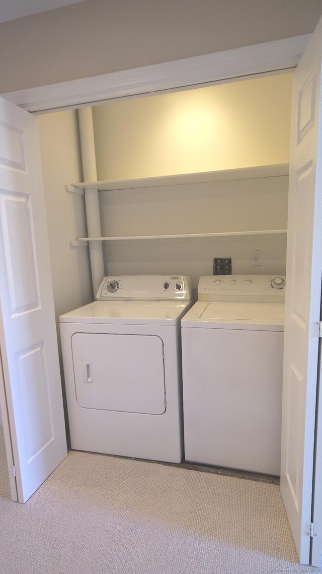 clothes washing area with light colored carpet and washing machine and clothes dryer