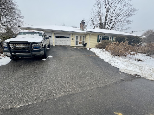 ranch-style home featuring a garage, driveway, and a chimney