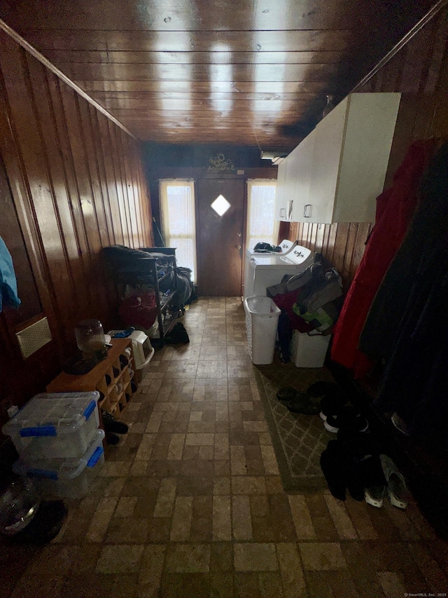 interior space featuring brick floor, wood ceiling, washer and clothes dryer, and wooden walls