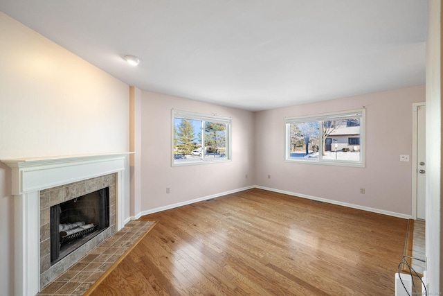 unfurnished living room featuring hardwood / wood-style flooring and a tiled fireplace