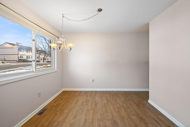 empty room with an inviting chandelier and hardwood / wood-style flooring