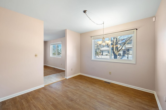 unfurnished dining area featuring hardwood / wood-style floors and a notable chandelier