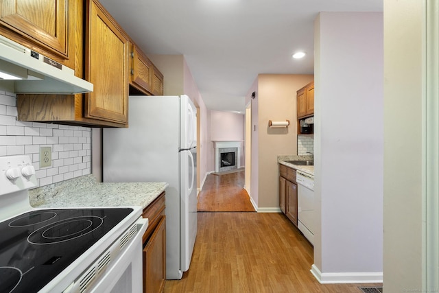 kitchen with sink, white appliances, backsplash, a fireplace, and light wood-type flooring