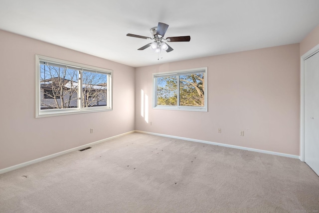 spare room with ceiling fan and light carpet