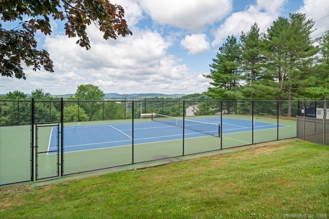 view of sport court featuring a mountain view and a lawn