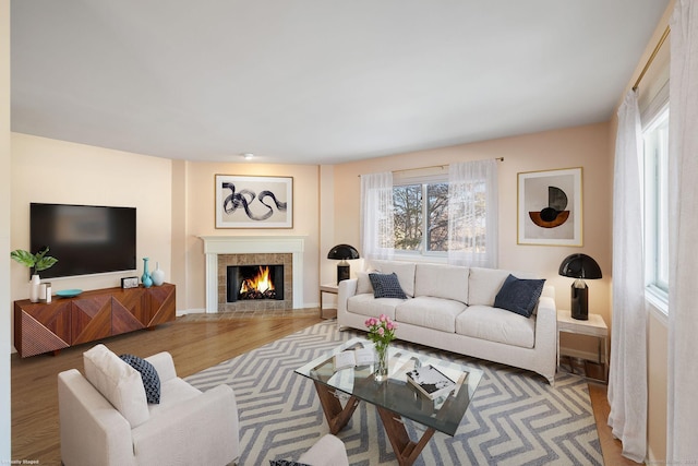 living room featuring a tiled fireplace and hardwood / wood-style floors