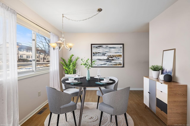 dining room featuring an inviting chandelier, a wealth of natural light, and dark wood-type flooring