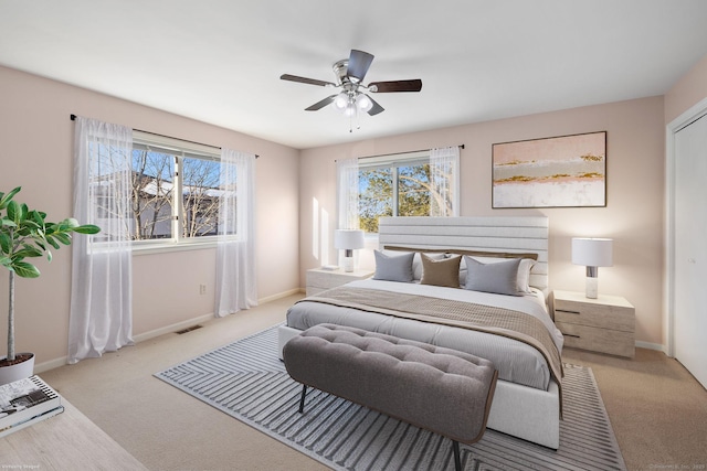 carpeted bedroom with ceiling fan and multiple windows