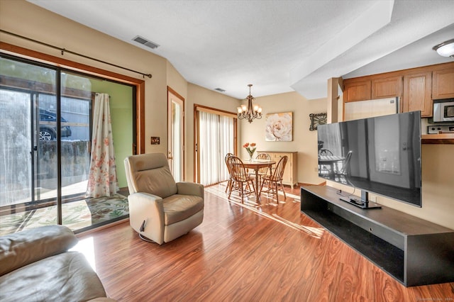 living room with hardwood / wood-style flooring, a chandelier, and a textured ceiling