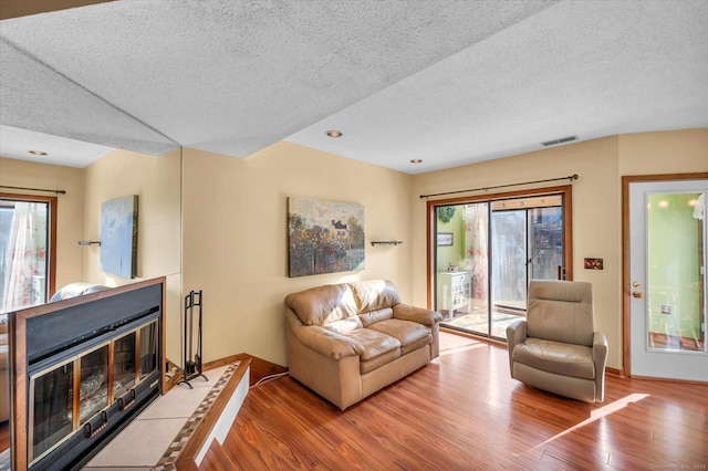 living room with wood-type flooring, a fireplace, and a textured ceiling