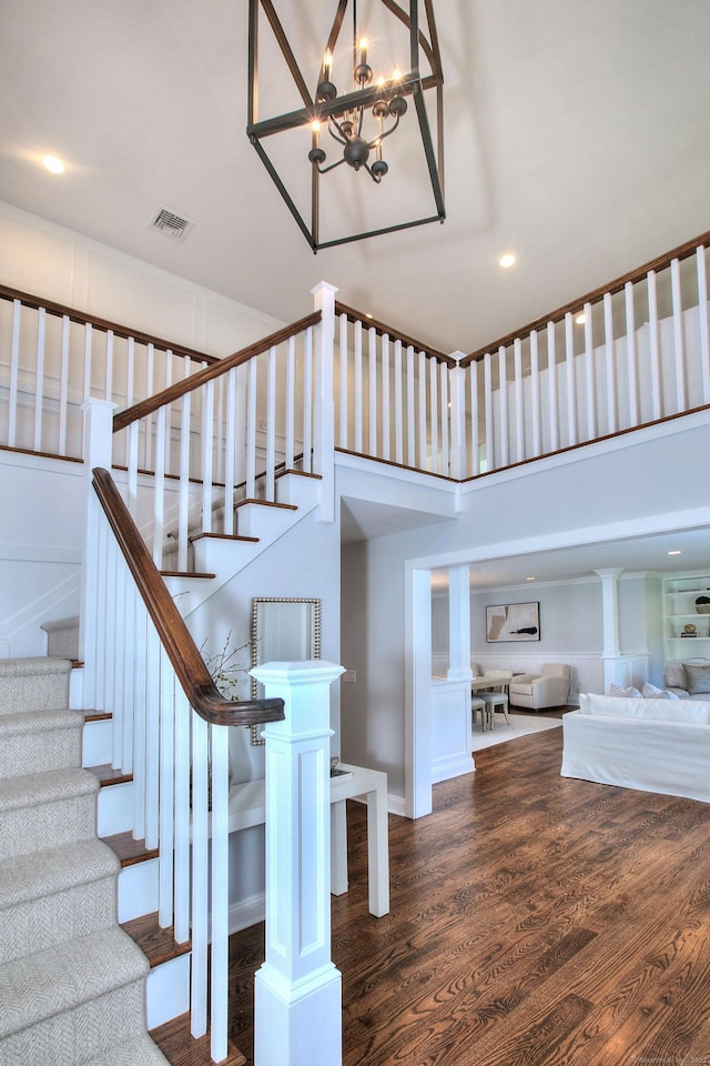 staircase with wood-type flooring and a towering ceiling