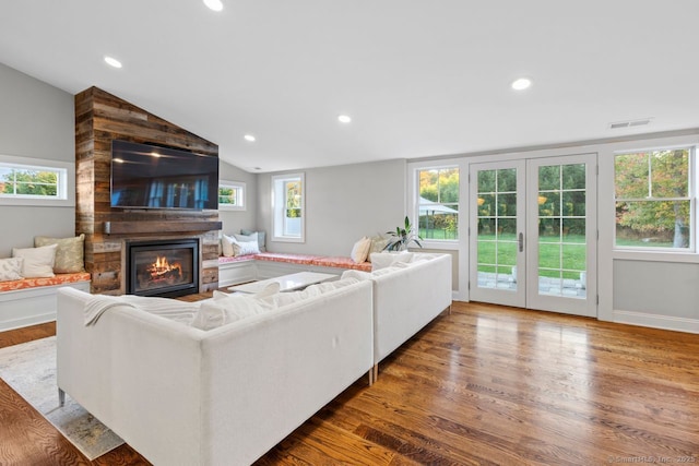 living room featuring lofted ceiling, dark hardwood / wood-style floors, and a large fireplace