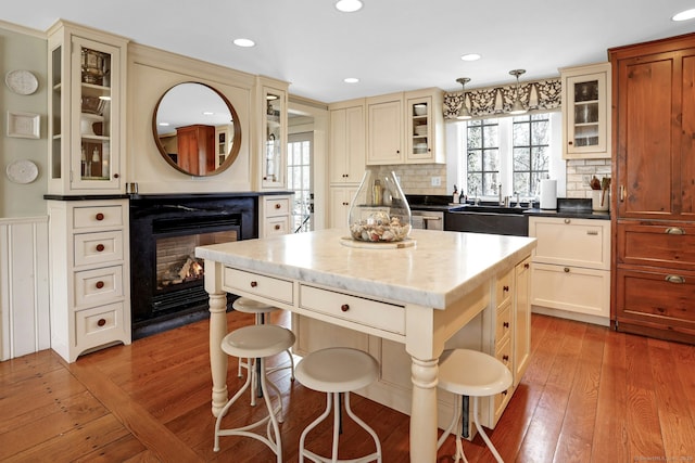 kitchen featuring sink, hardwood / wood-style flooring, a kitchen island, decorative light fixtures, and cream cabinetry