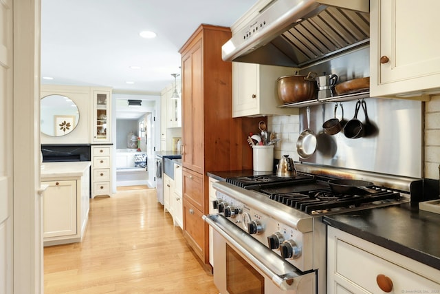 kitchen featuring light hardwood / wood-style flooring, extractor fan, backsplash, and high end stainless steel range