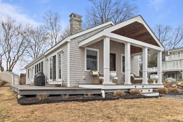 back of house featuring covered porch and a storage unit