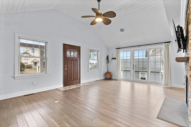 unfurnished living room with ceiling fan, high vaulted ceiling, a stone fireplace, and light hardwood / wood-style floors