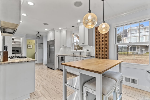 kitchen with appliances with stainless steel finishes, decorative light fixtures, sink, and white cabinets