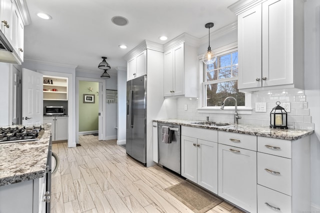 kitchen featuring stainless steel appliances, white cabinetry, and hanging light fixtures