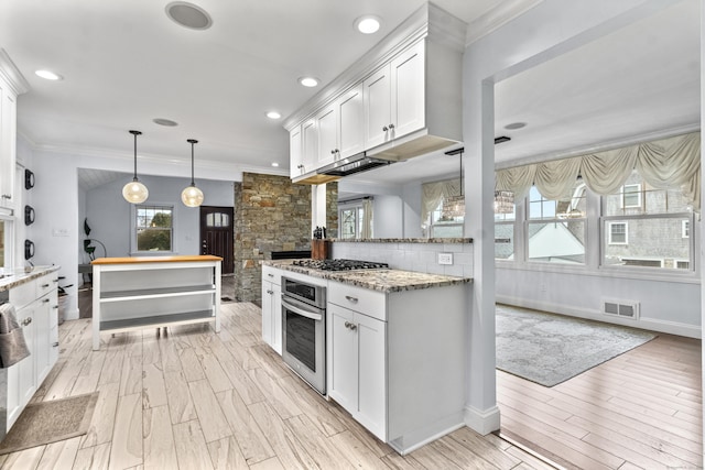 kitchen with stainless steel appliances, white cabinetry, light stone countertops, and decorative light fixtures