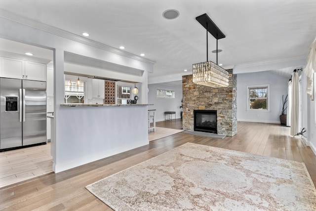 kitchen featuring a stone fireplace, decorative light fixtures, white cabinets, built in refrigerator, and light hardwood / wood-style flooring