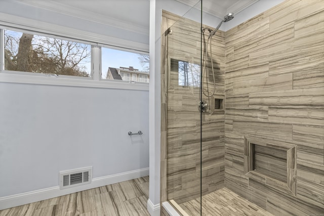 bathroom featuring a tile shower and ornamental molding